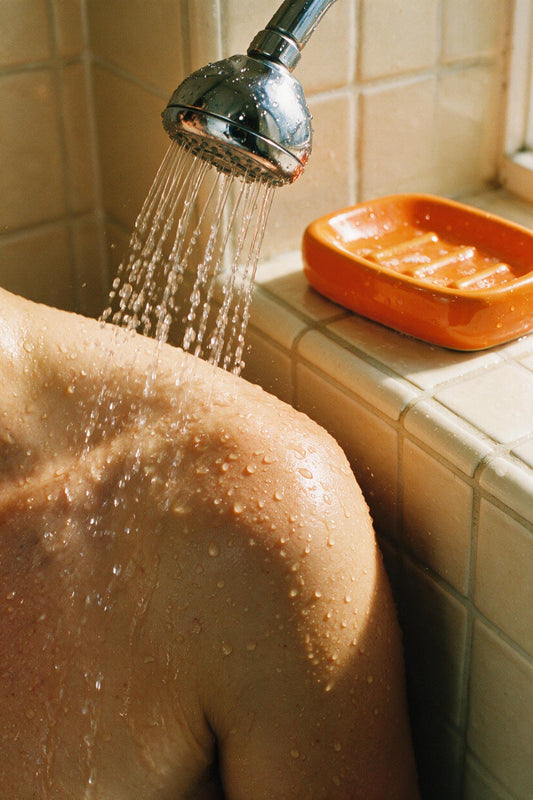 Cabezal de ducha con agua cayendo sobre la piel